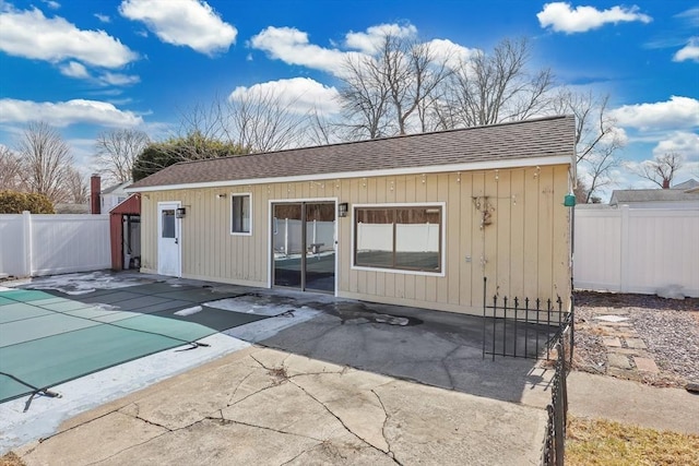 rear view of property with a fenced in pool, a patio, a shingled roof, and fence