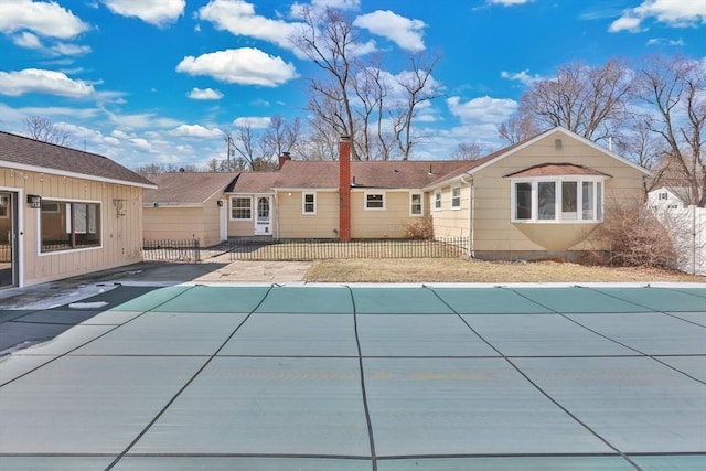 view of swimming pool featuring a covered pool, a patio, and fence