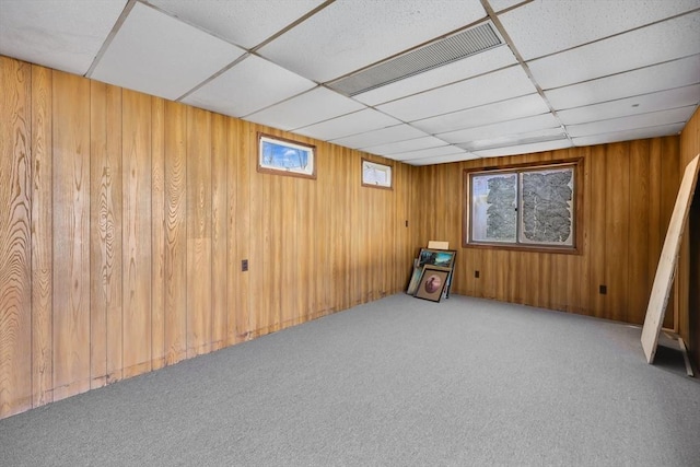 interior space with a wealth of natural light, carpet, visible vents, and wood walls