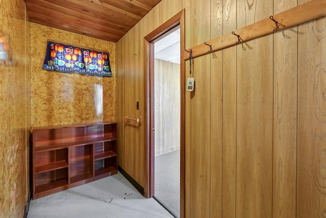 interior space featuring wood walls, wooden ceiling, and concrete floors