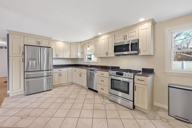 kitchen with dark countertops, cream cabinetry, and appliances with stainless steel finishes