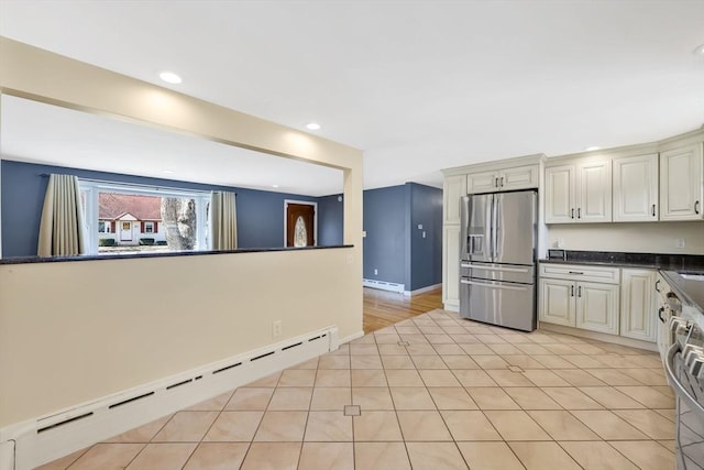 kitchen featuring a baseboard heating unit, dark countertops, stainless steel fridge, light tile patterned flooring, and a baseboard radiator