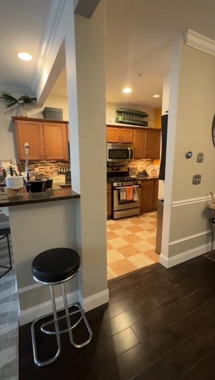 5 Lincoln Ln Unit 5, Grafton, MA 01536 - kitchen with stainless steel appliances, crown molding, dark countertops, a breakfast bar area, and brown cabinets