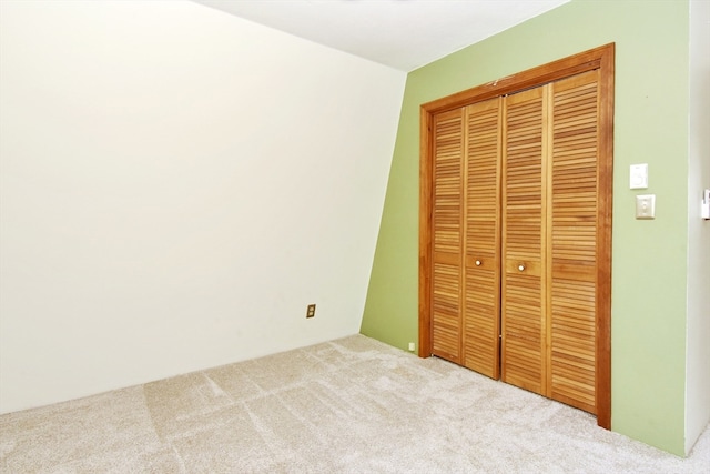 unfurnished bedroom featuring light colored carpet and a closet