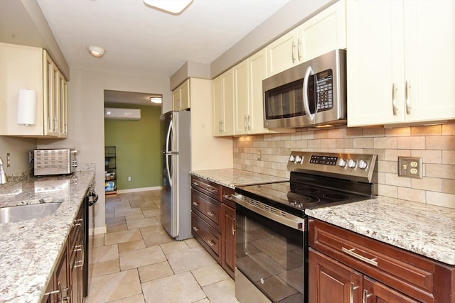 kitchen with sink, stainless steel appliances, light stone counters, a wall mounted AC, and decorative backsplash