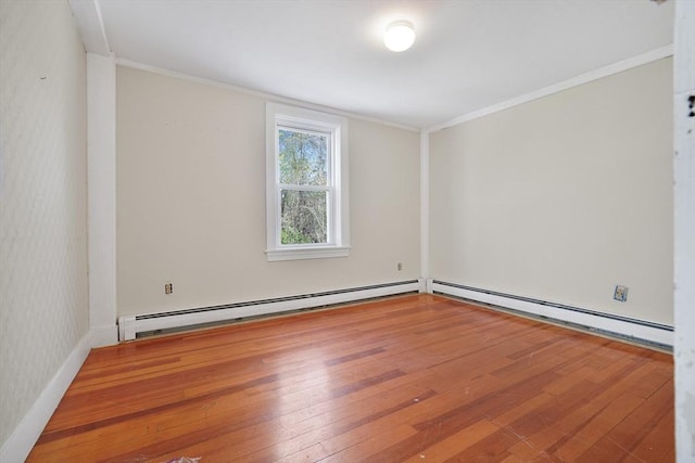 empty room featuring wood-type flooring, crown molding, and a baseboard heating unit