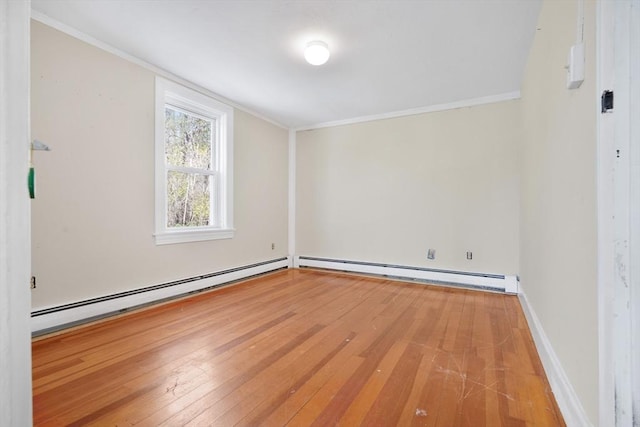 spare room featuring a baseboard heating unit, ornamental molding, and hardwood / wood-style floors