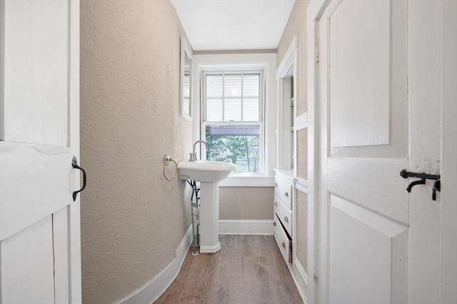 bathroom with baseboards, a textured wall, and wood finished floors