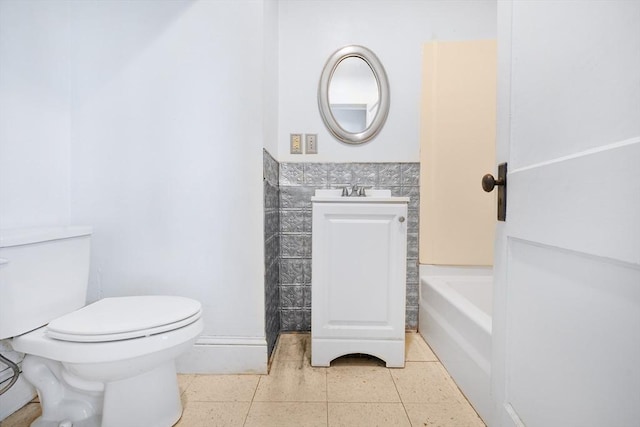 bathroom with wainscoting, vanity, toilet, tile patterned floors, and a washtub