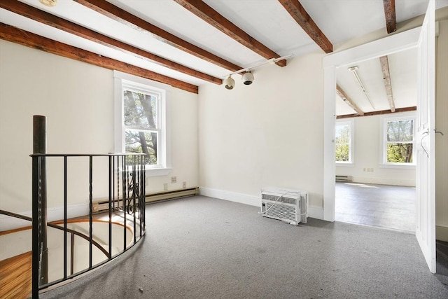 empty room featuring baseboards, a wall mounted AC, baseboard heating, and beamed ceiling