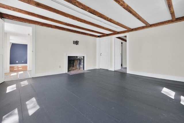 unfurnished living room featuring a fireplace with flush hearth and beamed ceiling