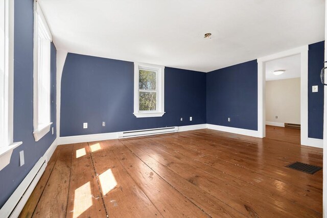 spare room featuring visible vents, hardwood / wood-style floors, baseboards, baseboard heating, and a baseboard radiator