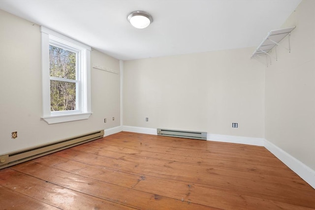 spare room with baseboards, baseboard heating, and hardwood / wood-style floors