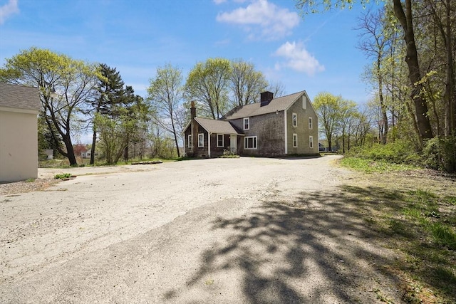 view of front of property featuring dirt driveway and a chimney