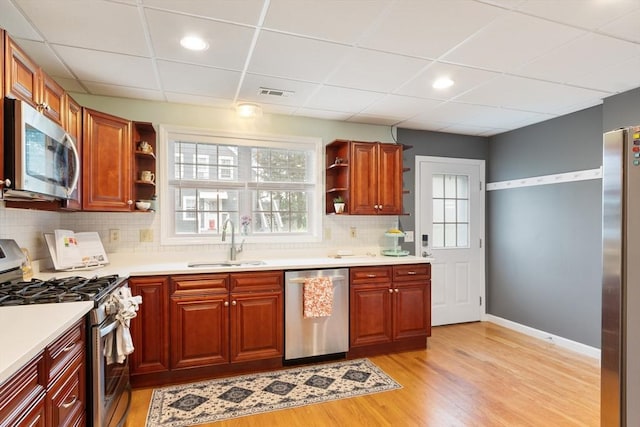 4 Fiske Ave, Chelmsford, MA 01863 - kitchen featuring appliances with stainless steel finishes, open shelves, light wood-type flooring, decorative backsplash, and light countertops