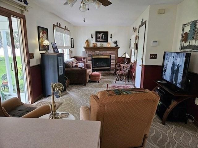 living room featuring ceiling fan, a wealth of natural light, and a fireplace