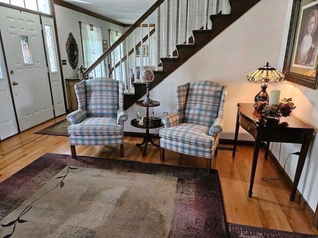 living area with wood-type flooring and ornamental molding