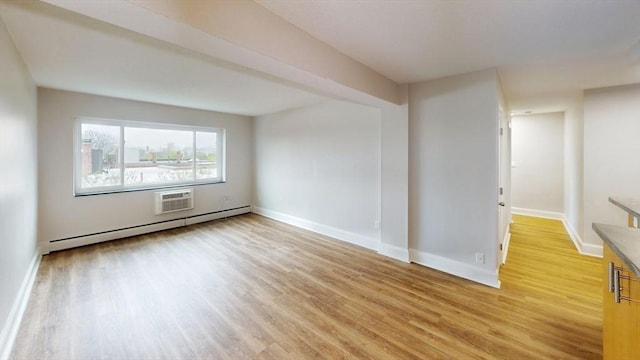 empty room with baseboards, light wood-style flooring, baseboard heating, and a wall unit AC