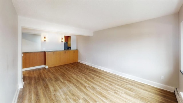 unfurnished room with baseboards and light wood-style flooring