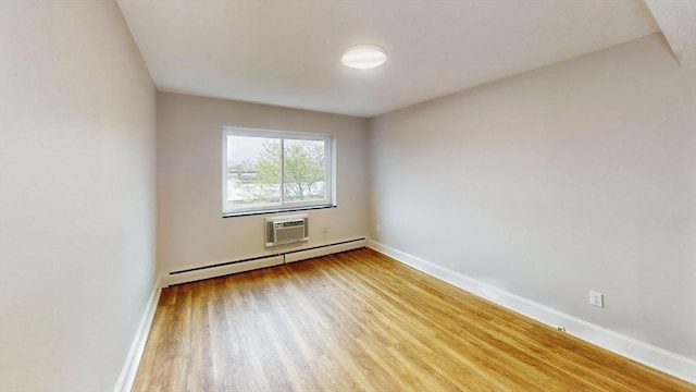 spare room featuring a baseboard heating unit, light wood-style floors, a wall unit AC, and baseboards