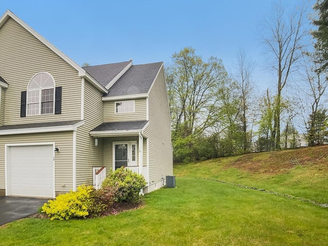 view of side of property featuring a garage, a lawn, cooling unit, a shingled roof, and driveway