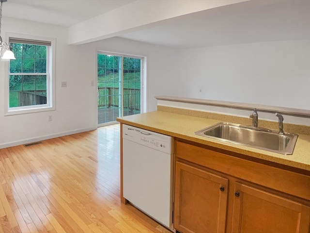 kitchen with white dishwasher, a sink, plenty of natural light, and brown cabinetry