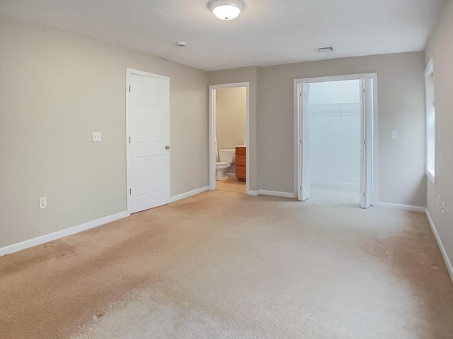 unfurnished bedroom with light carpet, baseboards, connected bathroom, and a closet