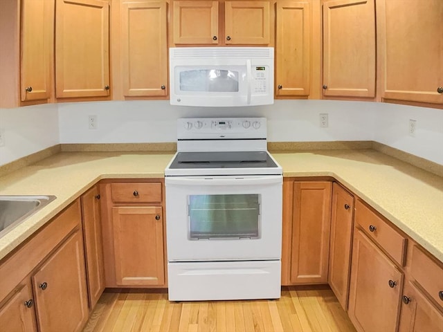 kitchen with white appliances, light countertops, and light wood finished floors