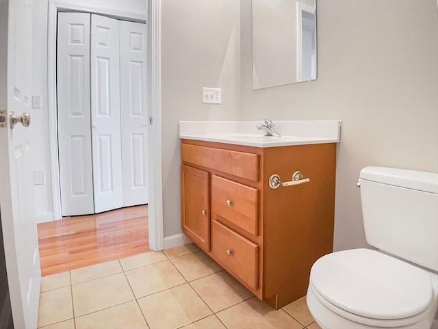 bathroom with toilet, tile patterned flooring, vanity, a closet, and baseboards