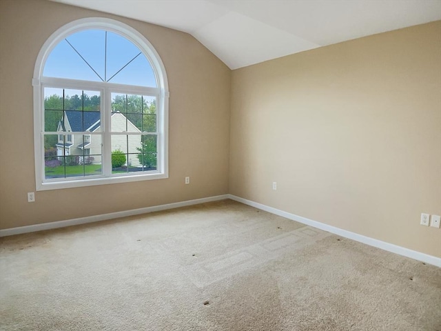 spare room featuring vaulted ceiling, baseboards, and carpet flooring