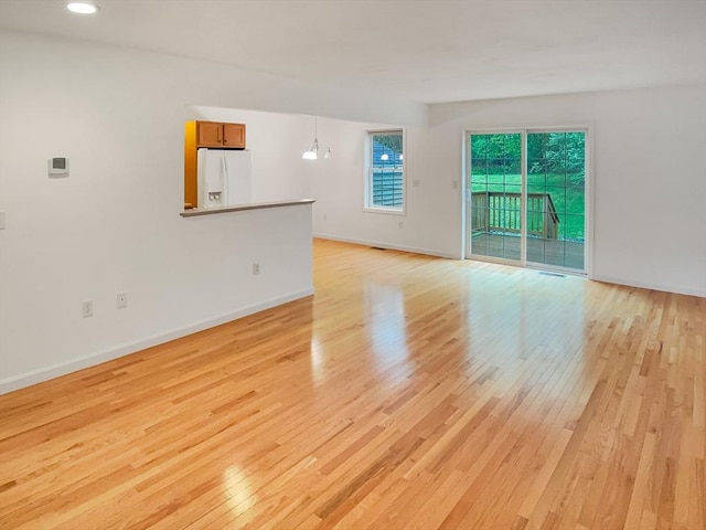 unfurnished living room featuring light wood-type flooring, baseboards, and recessed lighting