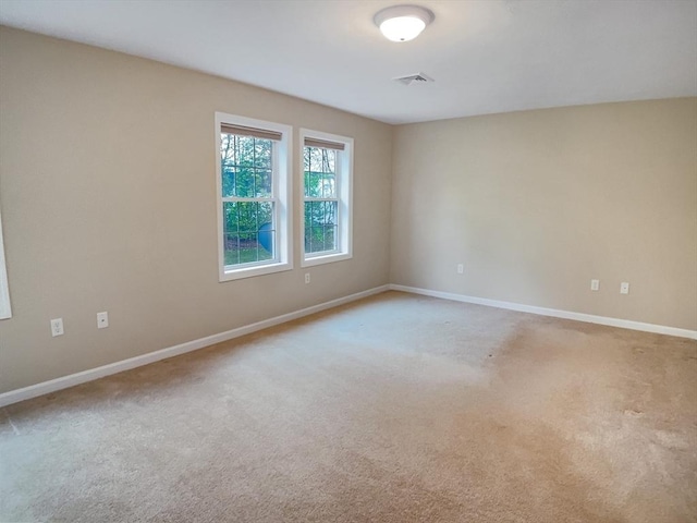 unfurnished room with light colored carpet and baseboards