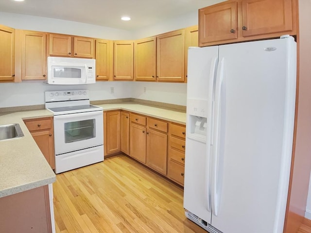 kitchen with white appliances, light wood finished floors, recessed lighting, and a sink