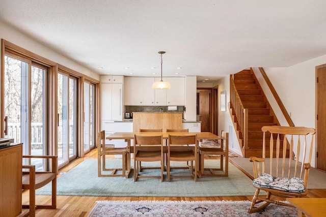 dining area featuring stairway, a healthy amount of sunlight, and light wood-style flooring