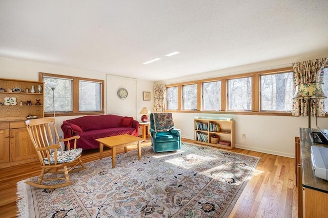 living area with a wealth of natural light, light wood-type flooring, and baseboards