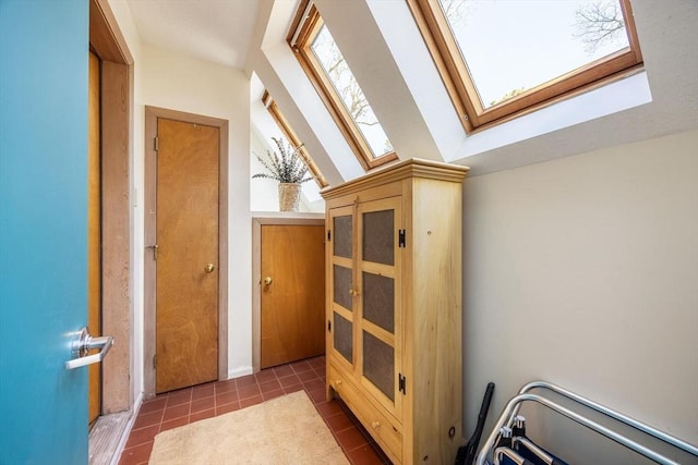 hallway featuring tile patterned floors and vaulted ceiling with skylight