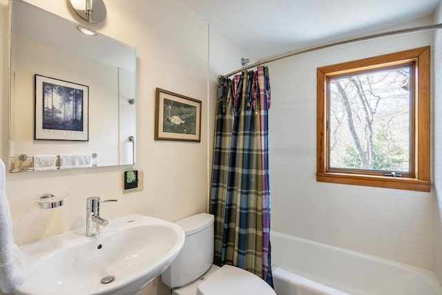 bathroom featuring toilet, shower / tub combo with curtain, and a sink