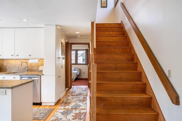 stairway featuring recessed lighting, a textured ceiling, and wood finished floors