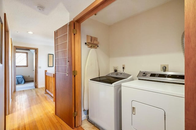 laundry room featuring laundry area, separate washer and dryer, light wood-type flooring, and baseboards