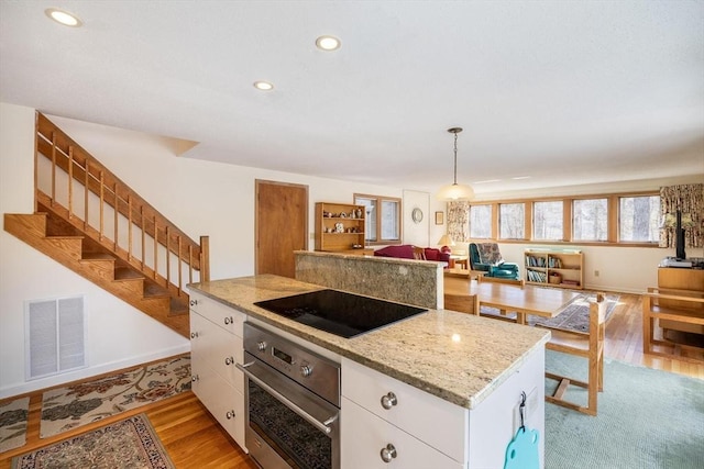 kitchen featuring visible vents, oven, light wood-style flooring, white cabinetry, and black electric cooktop