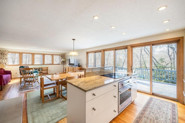 kitchen featuring light wood-type flooring, white cabinetry, oven, and black electric cooktop