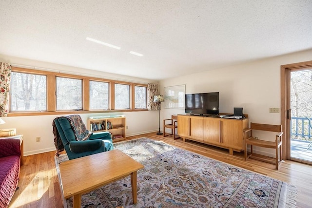 living room with light wood-style floors, baseboards, and a textured ceiling