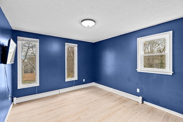 unfurnished room with baseboards, a textured ceiling, and wood finished floors