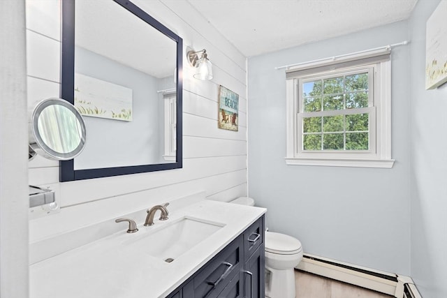 bathroom with a baseboard radiator, toilet, wood finished floors, and vanity