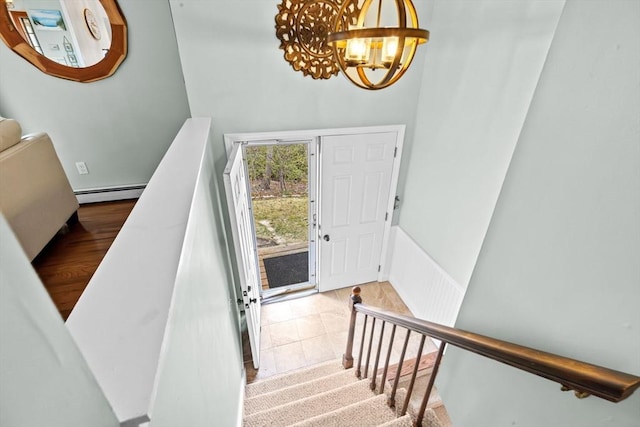 stairs featuring a chandelier and baseboard heating