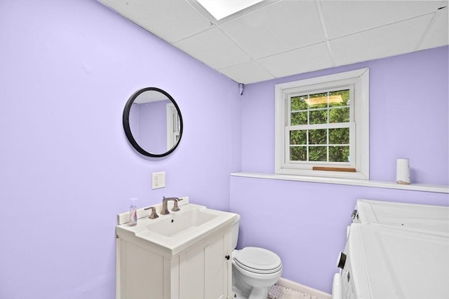bathroom featuring toilet, a drop ceiling, washer / clothes dryer, and vanity