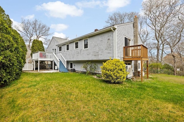 back of property featuring a deck, a chimney, and a lawn