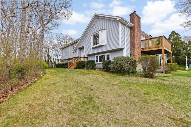 rear view of house with a chimney, a yard, and a wooden deck