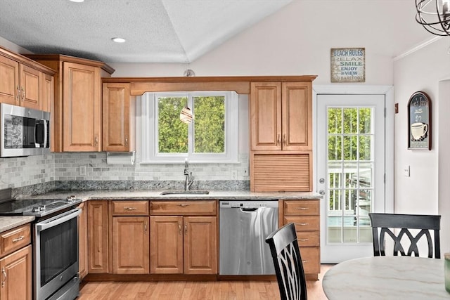 kitchen featuring a sink, vaulted ceiling, decorative backsplash, and appliances with stainless steel finishes