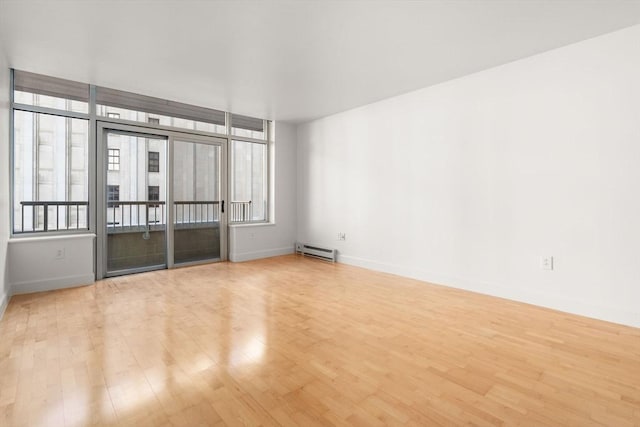 empty room featuring baseboard heating and light hardwood / wood-style floors